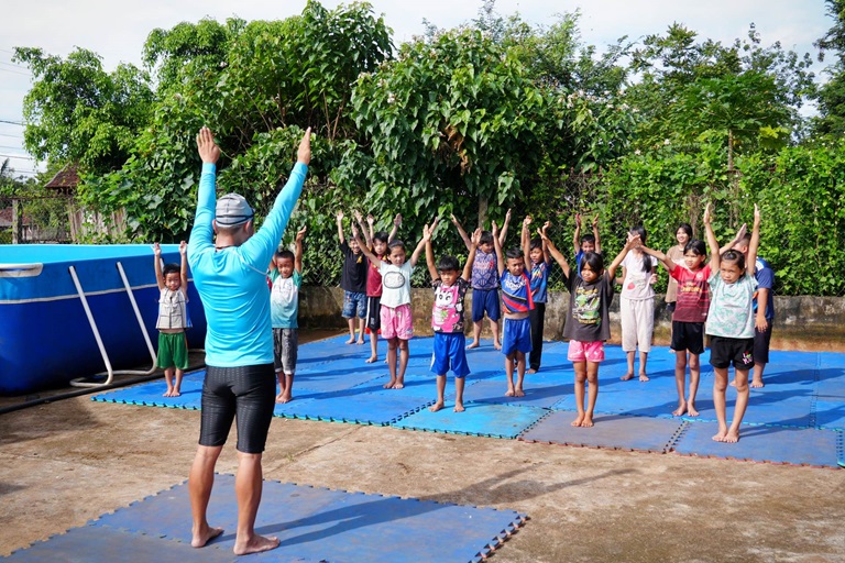 Mai Van Chuyen instructs children to warm up before their swimming lesson. WHO / Ho Chi Cuong